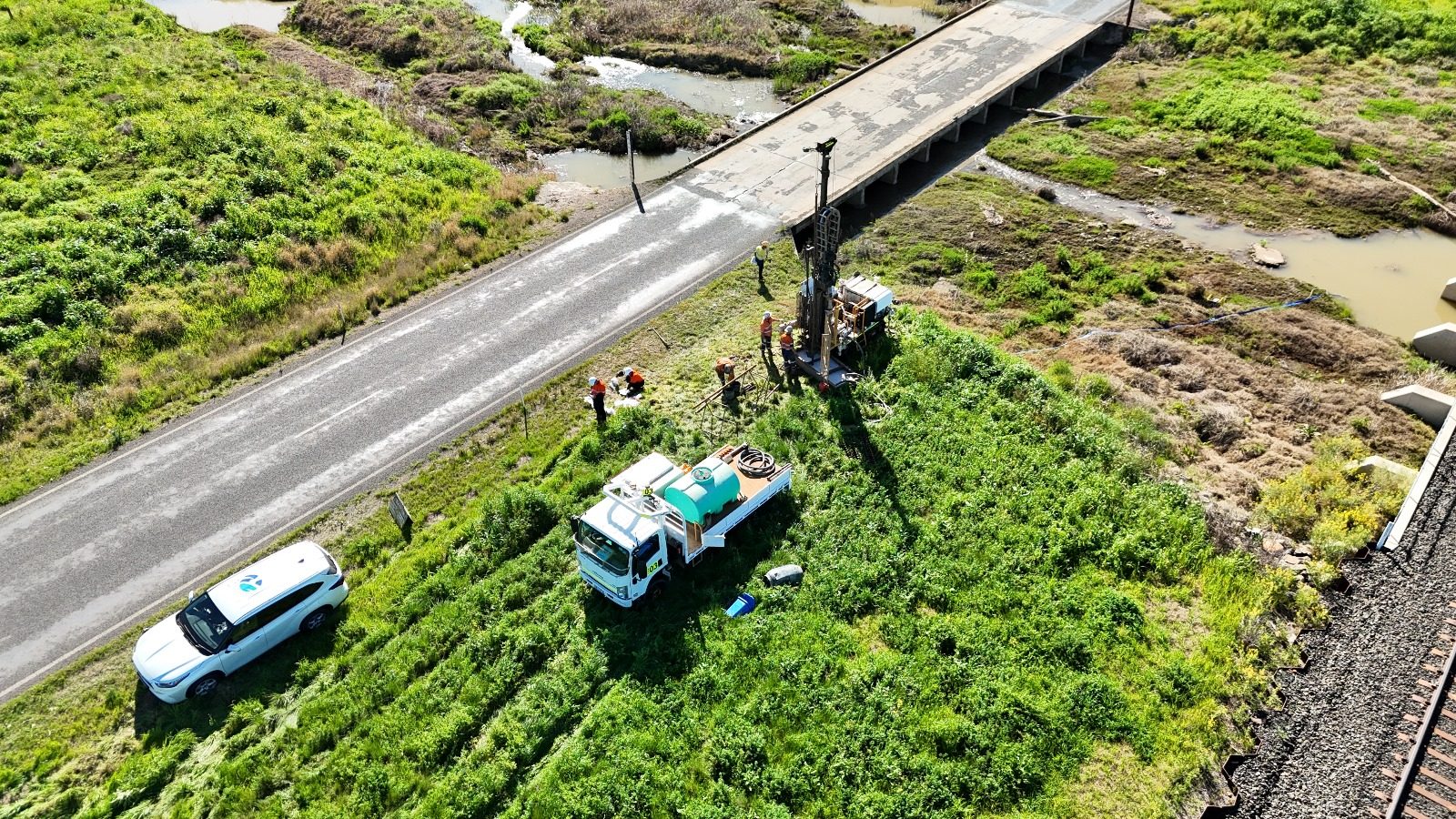 Aerial view of a drilling rig beside a road bridge