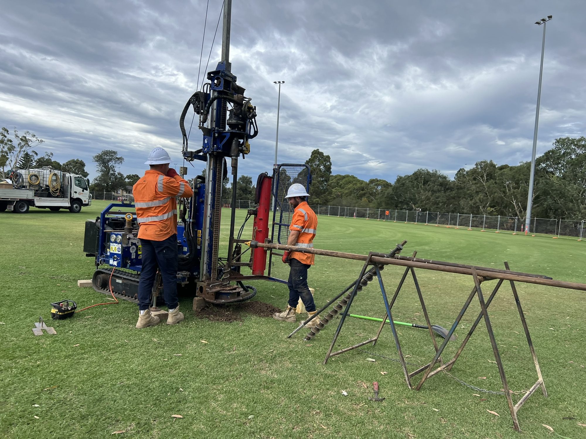 Geotechnical drilling rig and crew on a sports oval